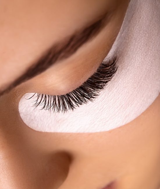 Eyelash Extension Procedure. Close up view of beautiful female eye with long eyelashes, smooth healthy skin